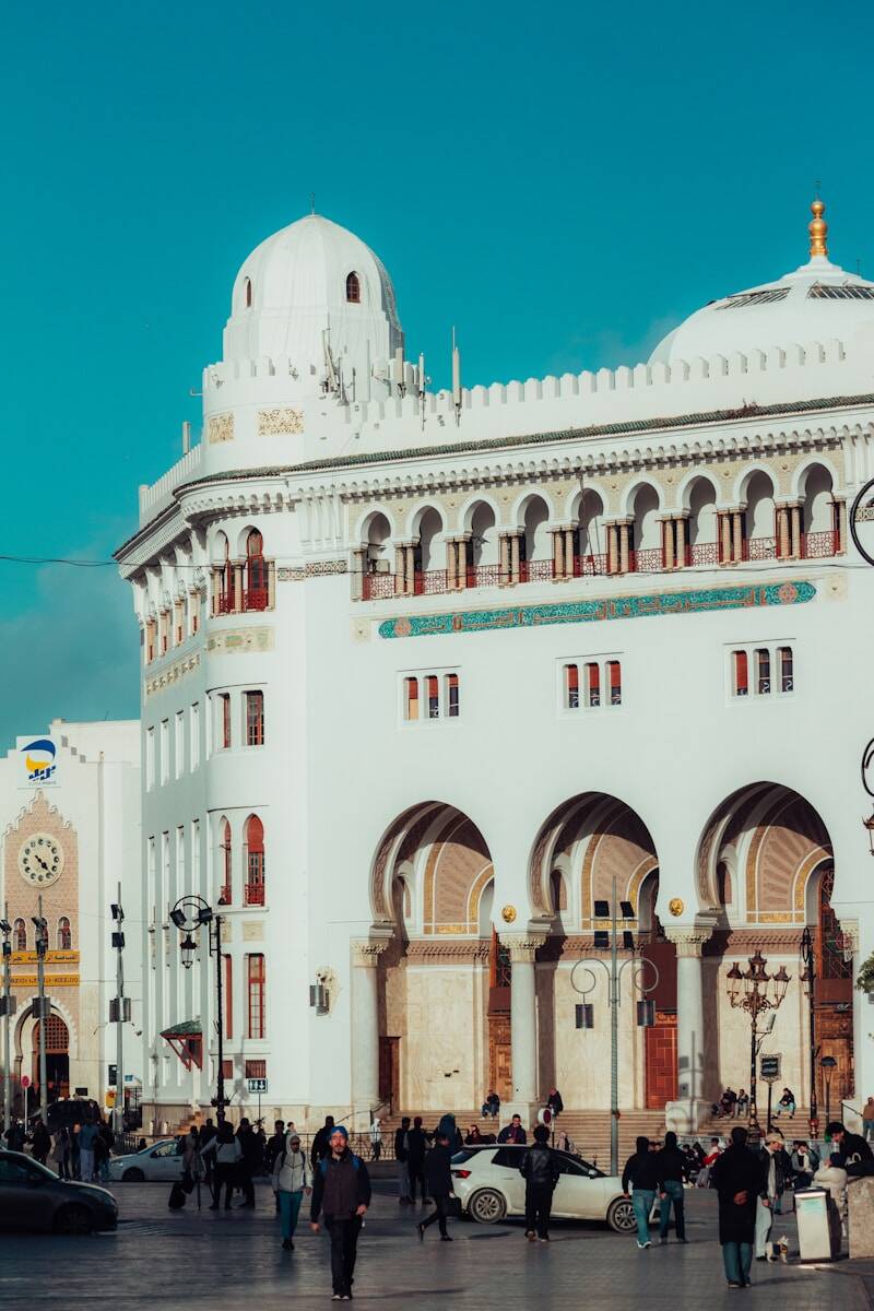 People walking in front of ornate white building with arches
